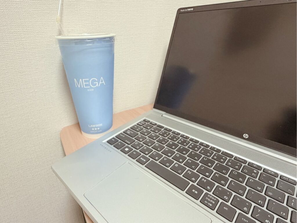 ノートパソコン横に置いたローソンのメガサイズアイスコーヒー