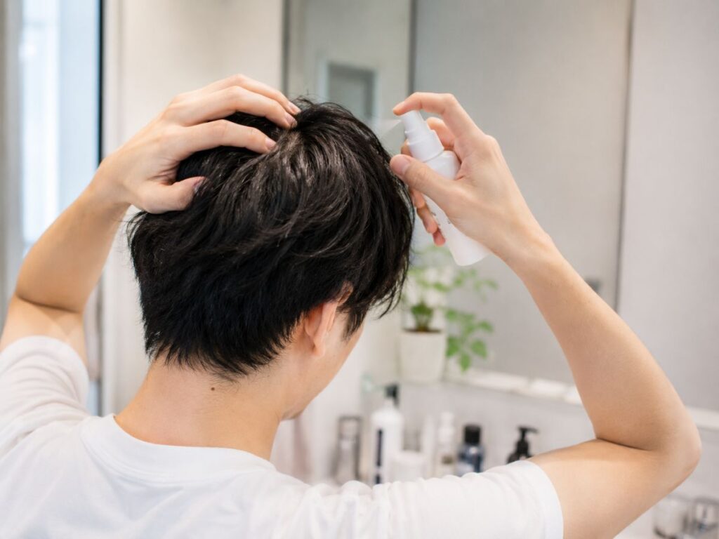 頭皮にスキャルプトナーをスプレーして保湿ケアをしている様子